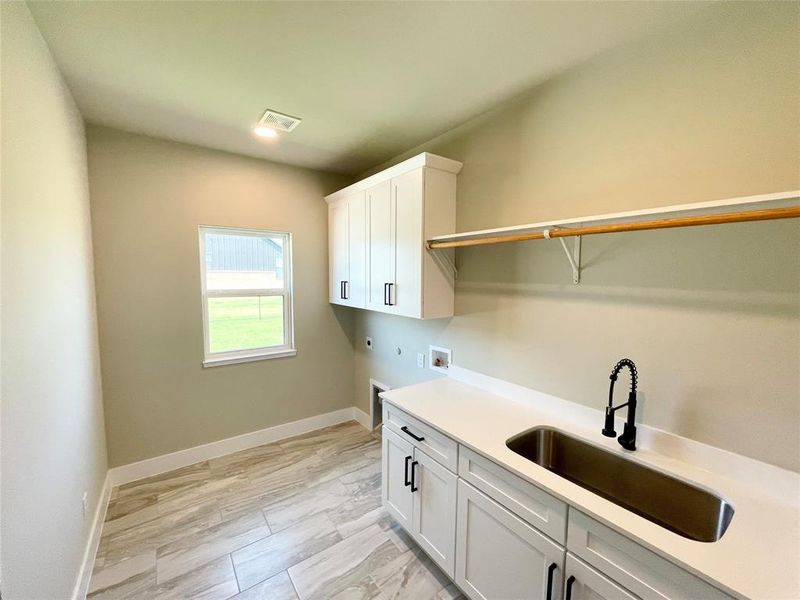 Washroom featuring sink, cabinets, hookup for an electric dryer, hookup for a washing machine, and light tile patterned floors