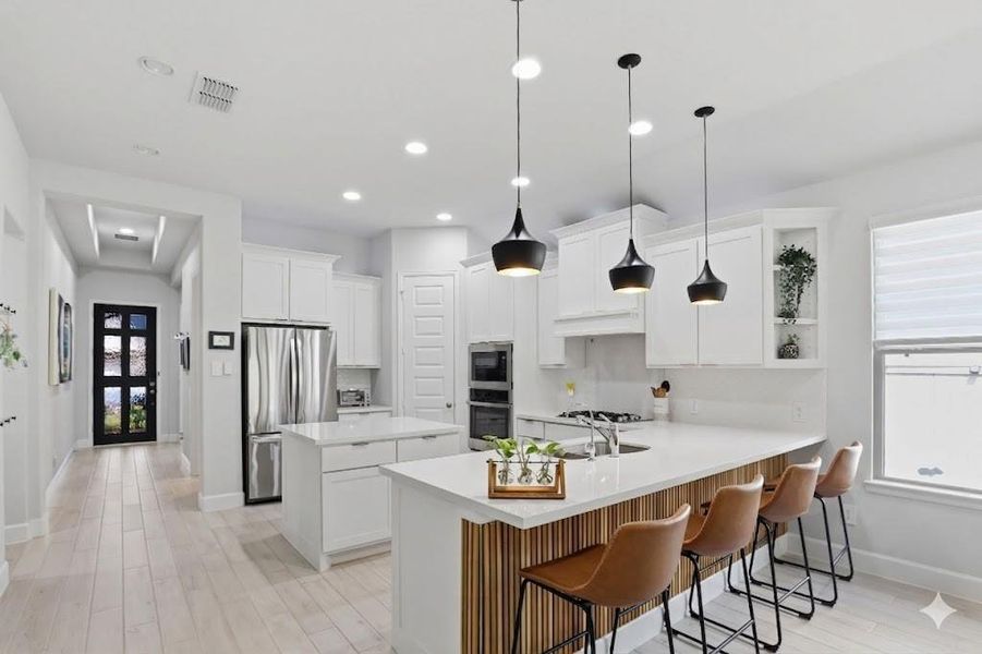 The oversized island features crisp white cabinetry and a breakfast bar finished with custom wood detailing.