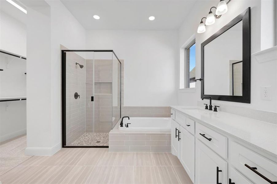 Modern bathroom featuring a soaking tub, glass-enclosed shower with tiled walls and pebble flooring, a wide vanity with white cabinetry, a single sink, and matte black hardware Modern bathroom featuring a soaking tub, glass-enclosed shower with tiled walls and pebble flooring, a wide vanity with white cabinetry, a single sink, and matte black hardware