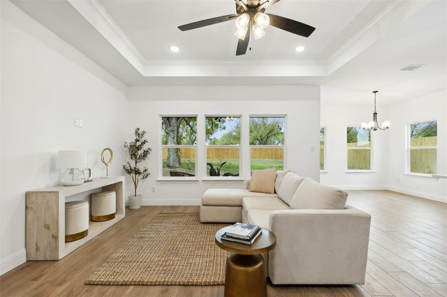 Living room featuring light hardwood / wood-style floors, a raised ceiling, and crown molding