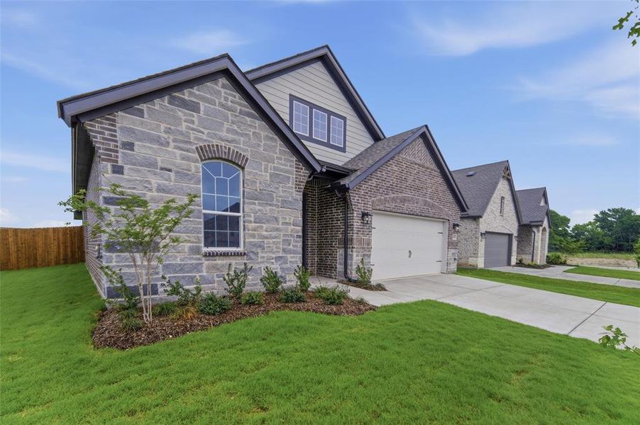 Stone and brick exterior with a distinctive arched window, gabled rooflines, and a two-car garage