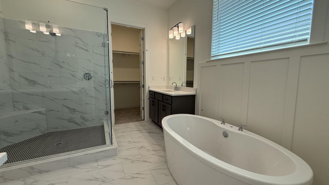 Bathroom with vanity, a marble finish shower, a soaking tub, a spacious closet, and light marble finish floors
