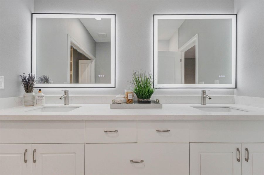 Modern primary bathroom offering a double vanity with dual LED mirrors and clean, fresh finishes throughout
