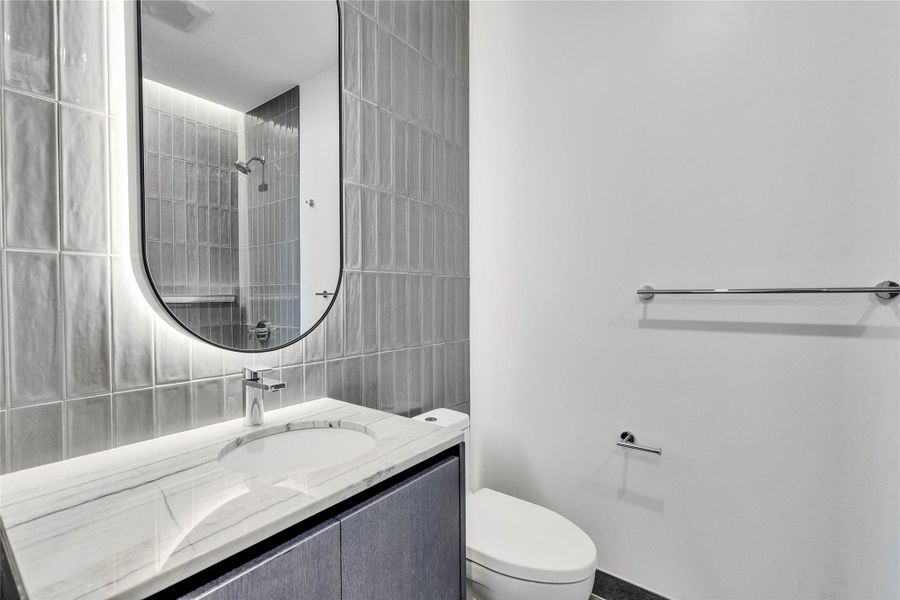 A contemporary vanity with a stone countertop pairs beautifully with modern vertical tiling. A contemporary vanity with a stone countertop pairs beautifully with modern vertical tiling.