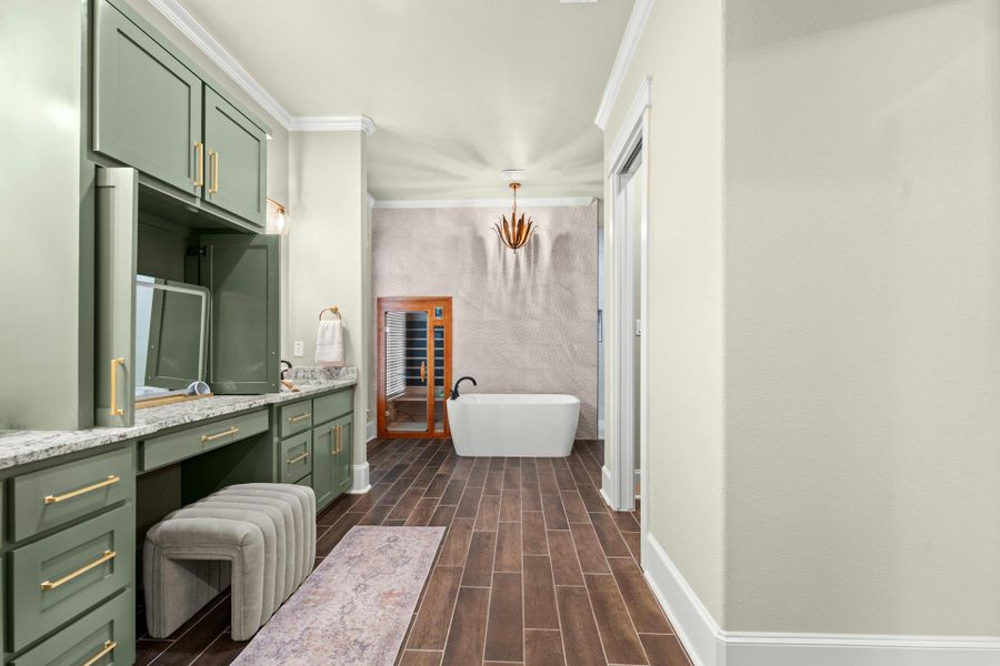 Spacious bathroom featuring a freestanding soaking tub, wood-finish flooring, and a vanity with green cabinetry and stone countertops