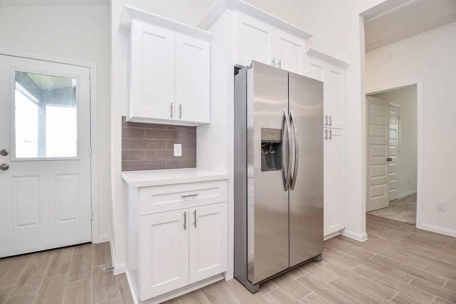 Notice more cabinetry, a gorgeous styled backsplash, and a stainless steel fridge to complete this modern styled home. There backdoor offers quick accessibility to an expansive, plush green yard.