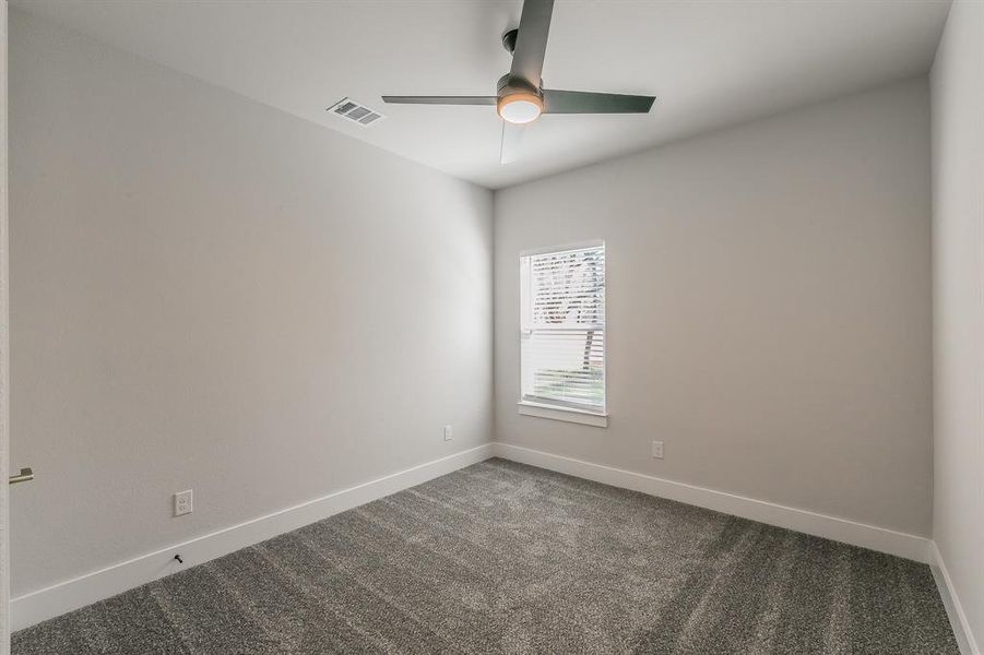 Unfurnished room with ceiling fan and dark carpet