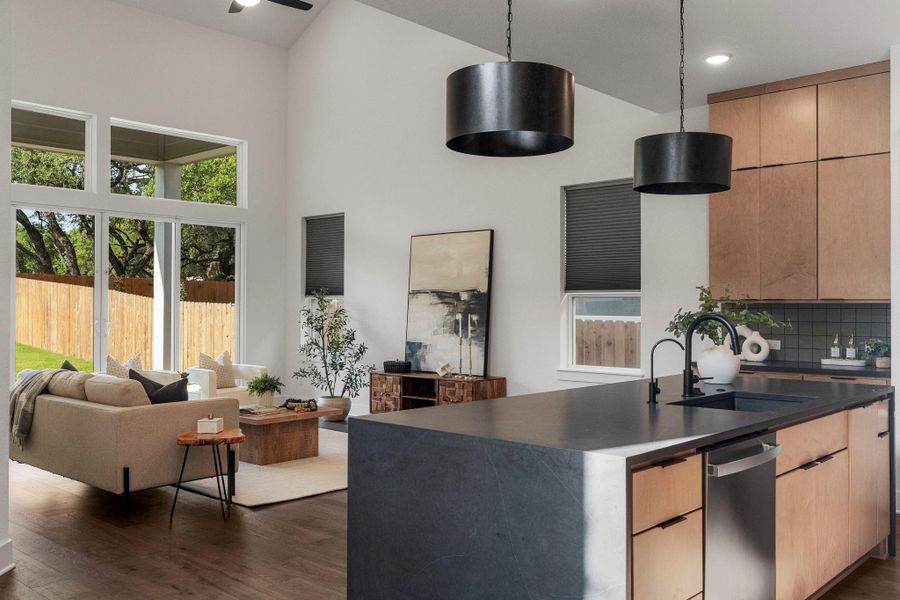 An open concept living and kitchen area features high ceilings and abundant natural light from large windows and glass doors.