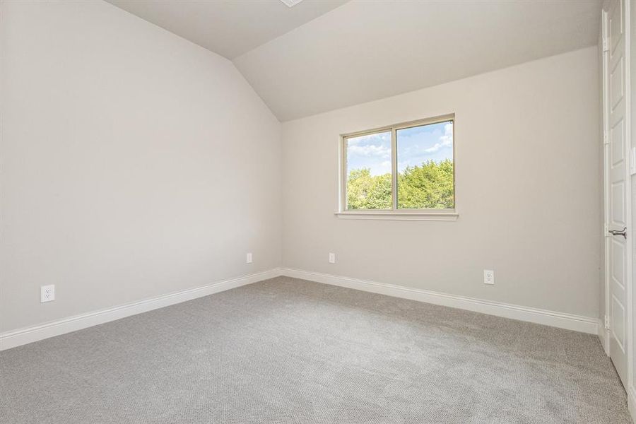 Unfurnished bedroom with vaulted ceiling and light carpet Unfurnished bedroom with vaulted ceiling and light carpet