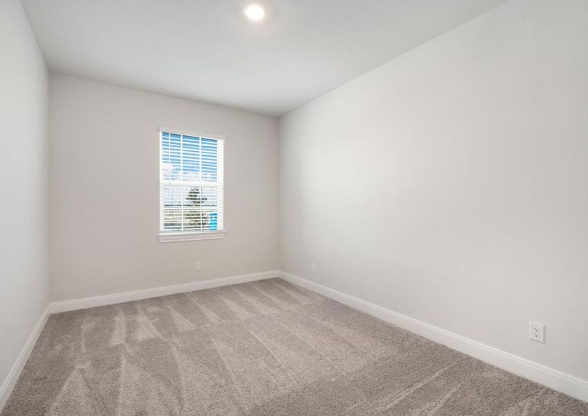 Spacious secondary bedroom with tan carpet and a single window.