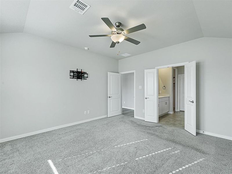 Unfurnished bedroom featuring carpet flooring, ceiling fan, connected bathroom, and vaulted ceiling