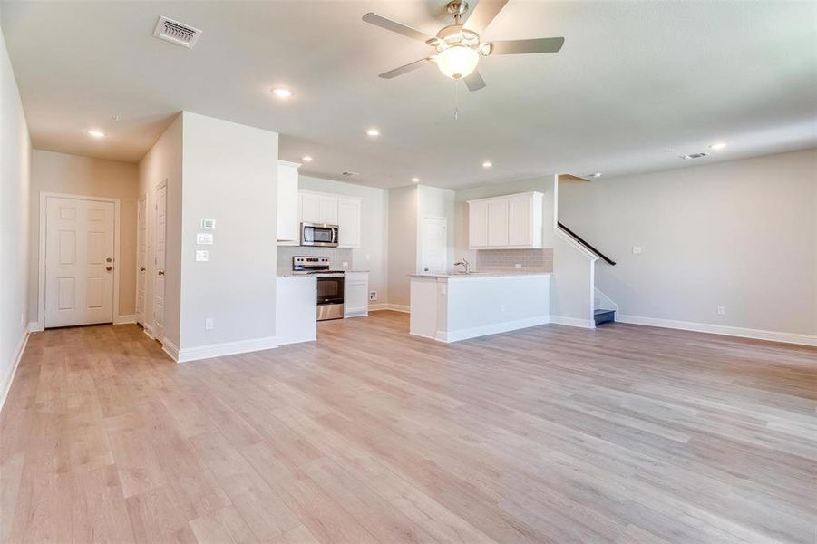 Unfurnished living room with ceiling fan, sink, and light wood-type flooring Unfurnished living room with ceiling fan, sink, and light wood-type flooring