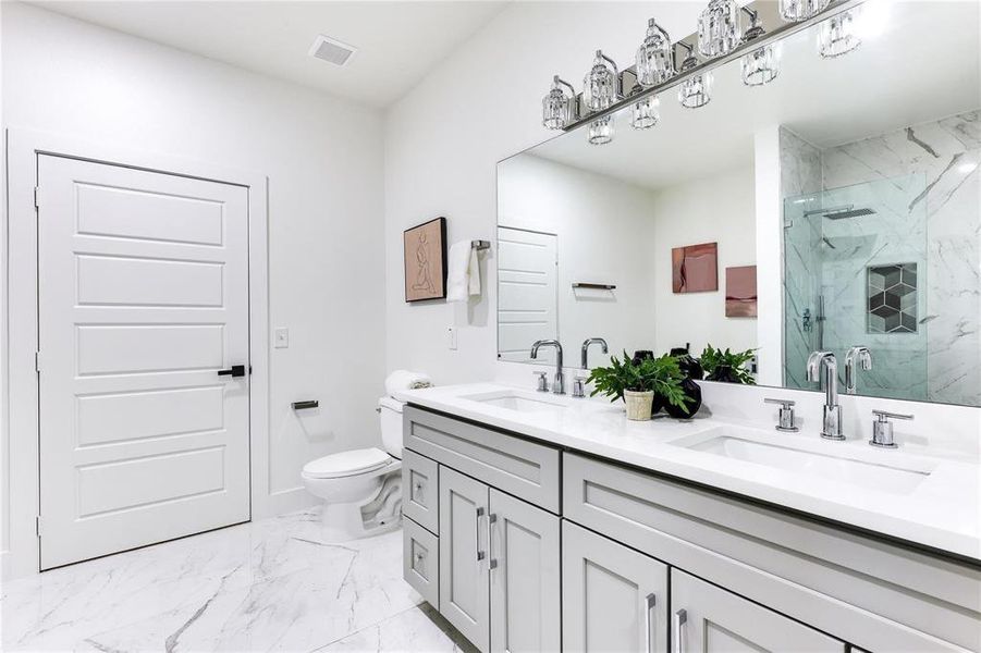 Bathroom featuring vanity, a shower with shower door, and toilet