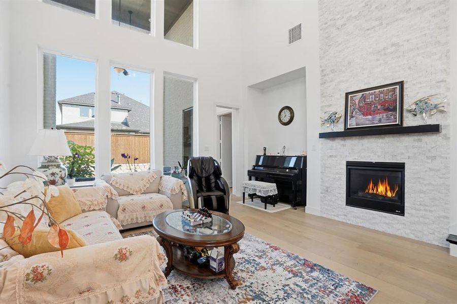 Living area with light wood-type flooring, a fireplace, and a high ceiling Living area with light wood-type flooring, a fireplace, and a high ceiling