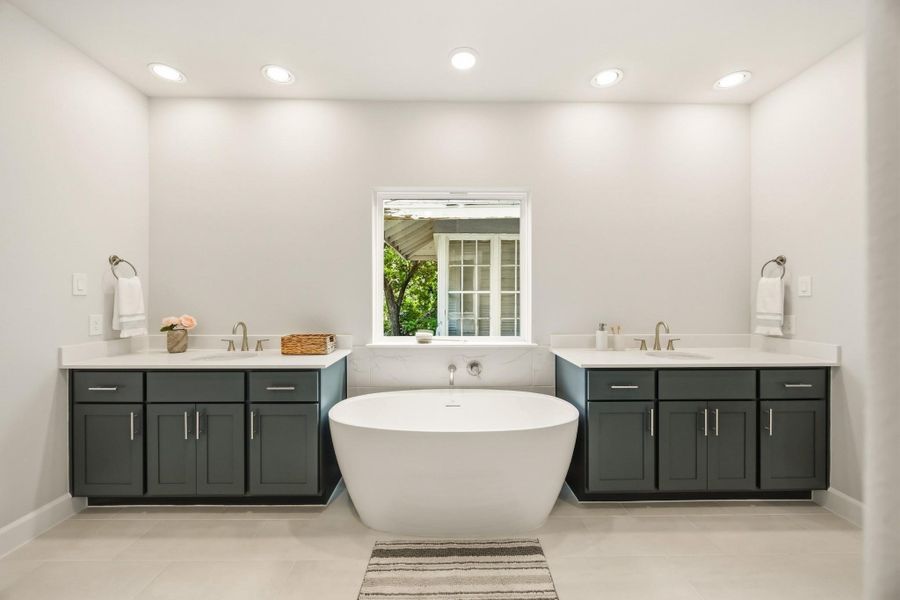Step into an oasis featuring a vessel tub set between dual vanities, framed by custom wood cabinets and quartz countertops, for an unwavering indulgence. Step into an oasis featuring a vessel tub set between dual vanities, framed by custom wood cabinets and quartz countertops, for an unwavering indulgence.