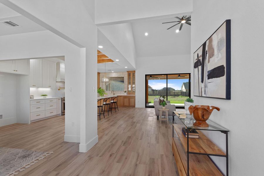 Hall featuring light wood-style floors, a high ceiling, and recessed lighting Hall featuring light wood-style floors, a high ceiling, and recessed lighting