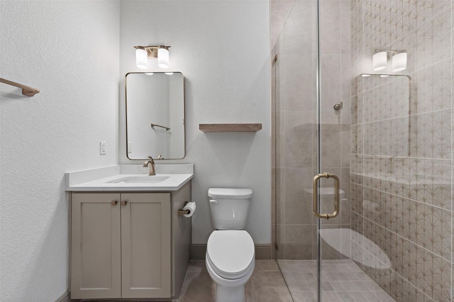 Bathroom with baseboards, toilet, a stall shower, and vanity