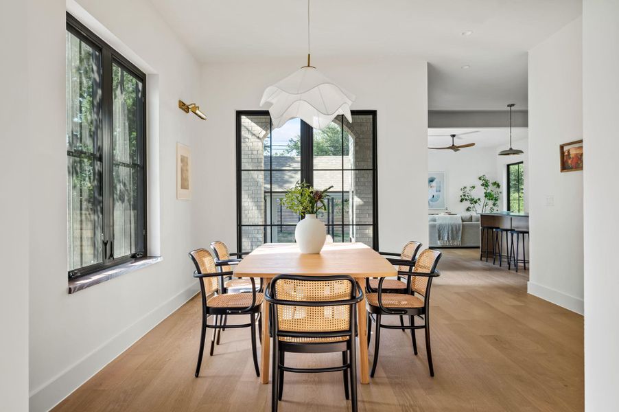 A graceful dining area, perfectly poised for gatherings, features expansive windows and light wood flooring.
