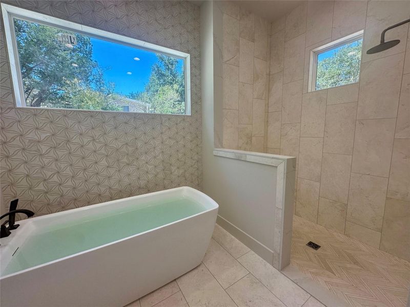 High ceilings and tall windows bring natural light into this modern bath featuring a soaking tub.