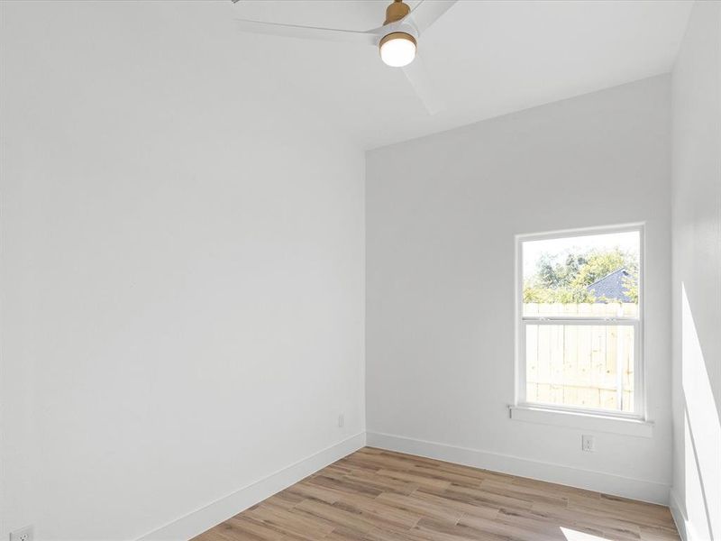Empty room featuring light wood-type flooring and a ceiling fan