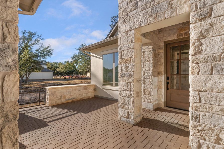 Entrance to property featuring stone siding and a patio area