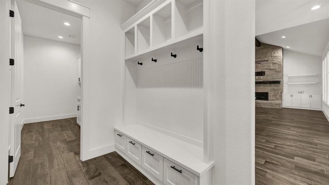 Mudroom featuring vaulted ceiling, dark wood-type flooring, and a stone fireplace