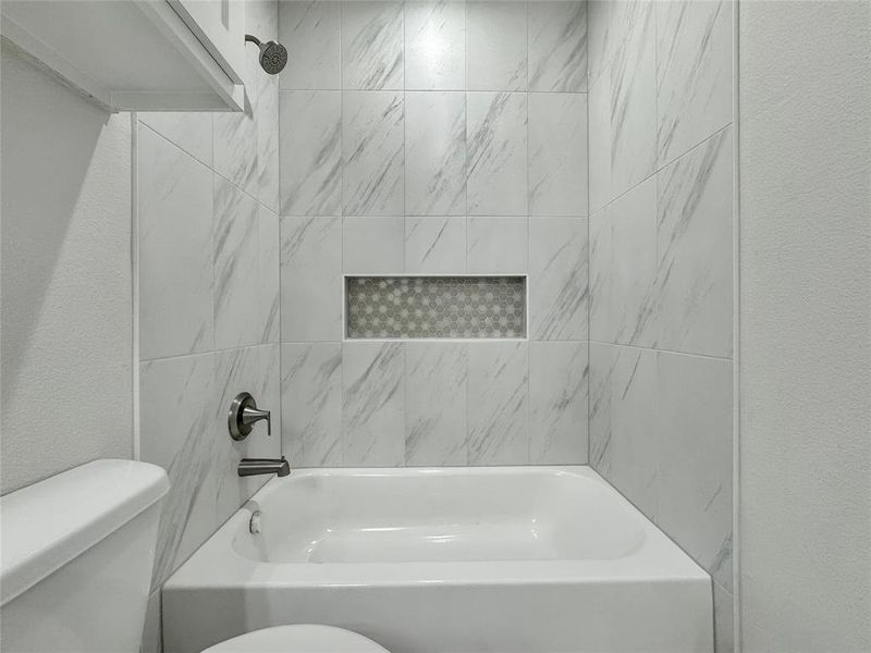 Bathroom featuring a textured wall and washtub / shower combination Bathroom featuring a textured wall and washtub / shower combination