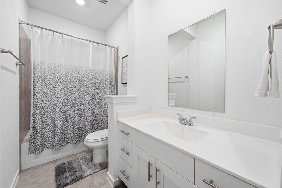 Bathroom featuring vanity, shower / bath combo with shower curtain, and light tile patterned flooring