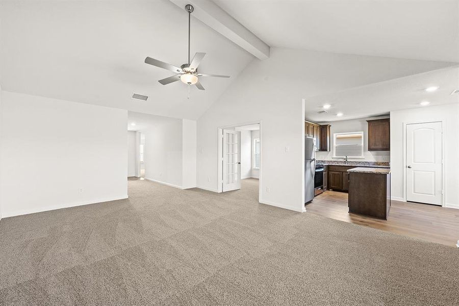 Unfurnished living room with light carpet, a ceiling fan, high vaulted ceiling, recessed lighting, and beamed ceiling