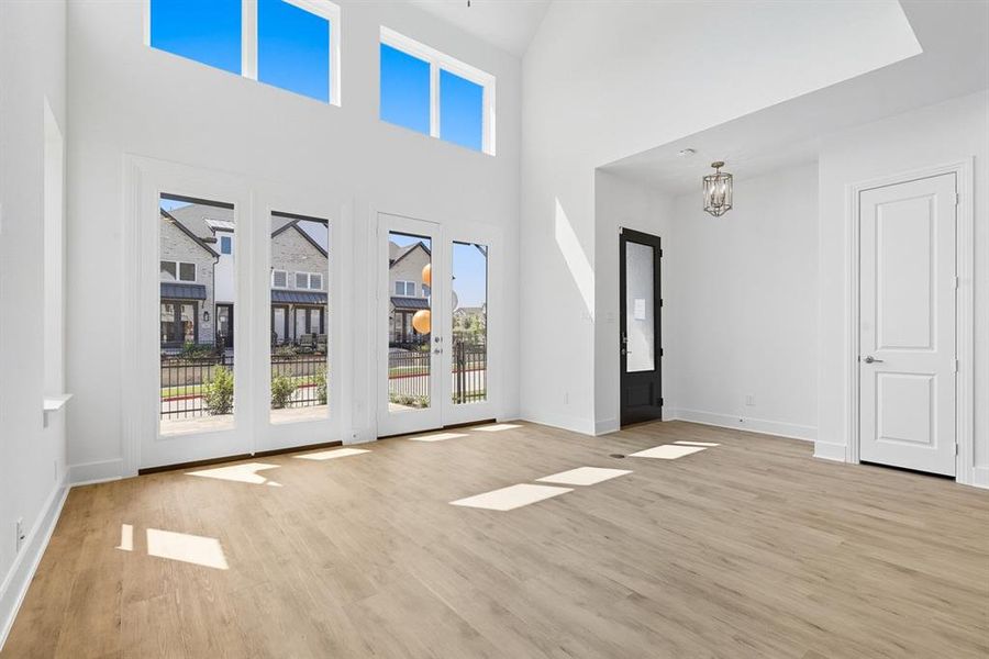 Foyer entrance with a high ceiling, light wood finished floors, a chandelier, and french doors Foyer entrance with a high ceiling, light wood finished floors, a chandelier, and french doors