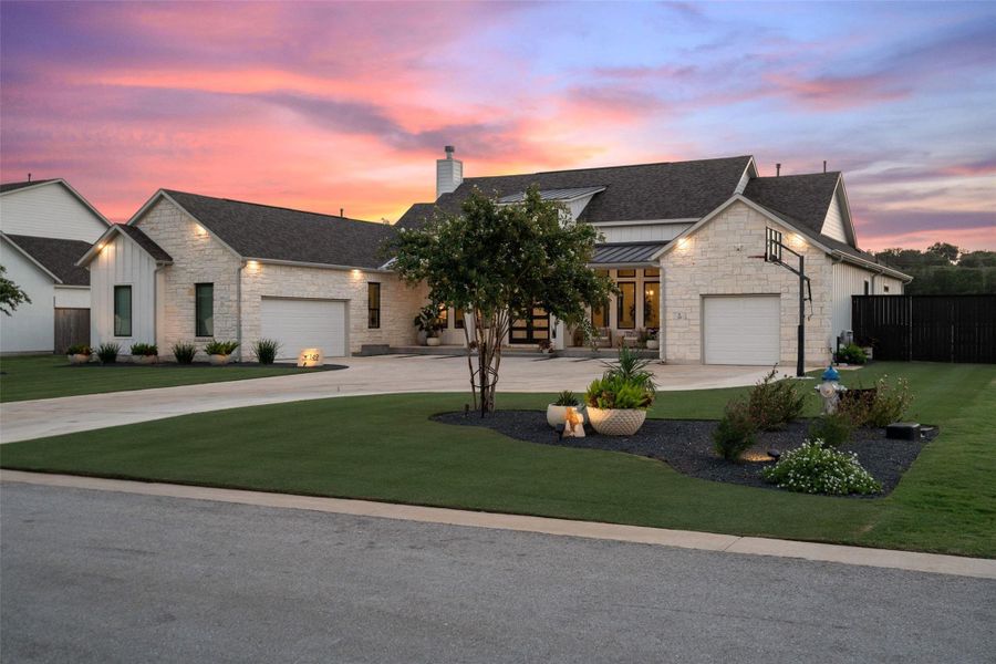 A well-manicured lawn and broad driveway enhance this inviting stone and siding residence at sunset. A well-manicured lawn and broad driveway enhance this inviting stone and siding residence at sunset.