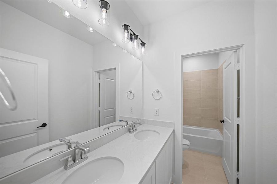 Full bath featuring double vanity and light tile patterned floors