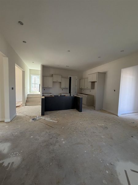 Open-concept living space featuring a kitchen with light-toned cabinetry and a dark-toned island foundation Open-concept living space featuring a kitchen with light-toned cabinetry and a dark-toned island foundation