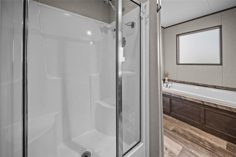 Full bathroom with a stall shower, light wood-style flooring, a bath, and ornamental molding Full bathroom with a stall shower, light wood-style flooring, a bath, and ornamental molding