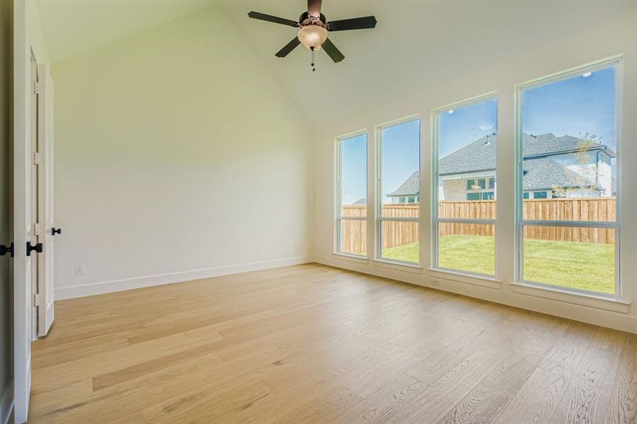 Unfurnished room with light wood-type flooring, high vaulted ceiling, and ceiling fan Unfurnished room with light wood-type flooring, high vaulted ceiling, and ceiling fan
