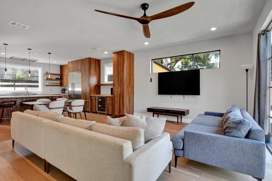 Living room featuring light wood-type flooring, recessed lighting, ceiling fan, and beverage cooler