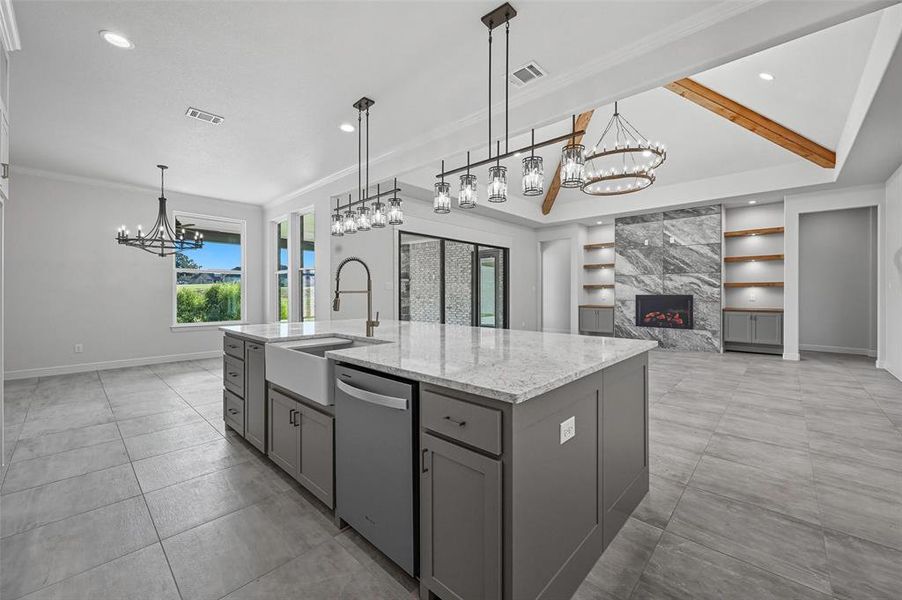 Kitchen with a chandelier, a high end fireplace, light stone countertops, an island with sink, and crown molding Kitchen with a chandelier, a high end fireplace, light stone countertops, an island with sink, and crown molding