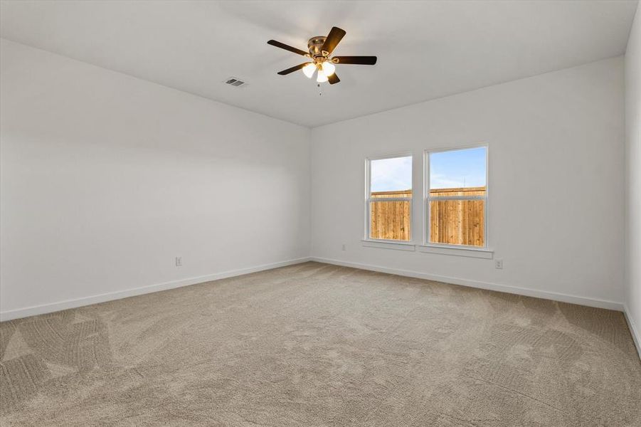 Carpeted master bedroom featuring ceiling fan