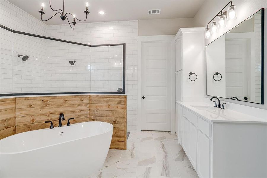 Bathroom featuring a bathtub, tile flooring, an inviting chandelier, and vanity with extensive cabinet space