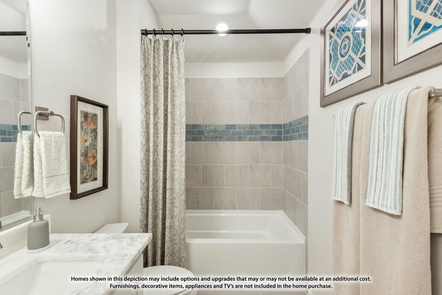 Bathroom with tiled tub and shower combo, marble countertop, and decorative blue tile accent strip.