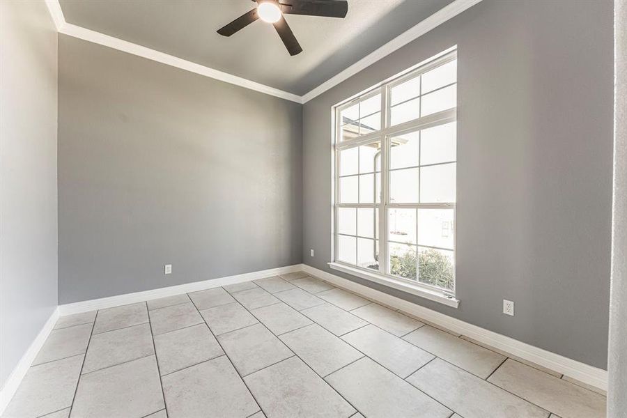 Tiled empty room featuring plenty of natural light, ornamental molding, and ceiling fan