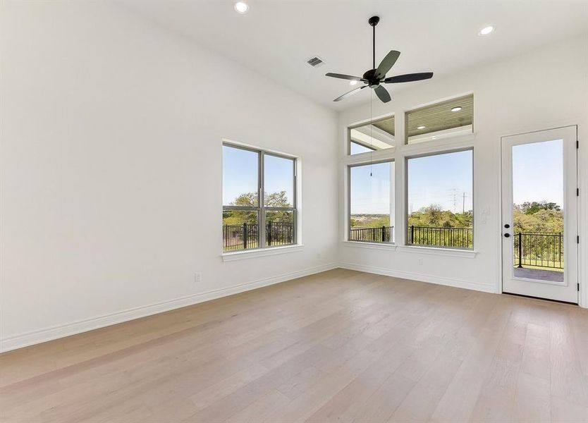 This room features high ceilings, light hardwood floors, and recessed lighting