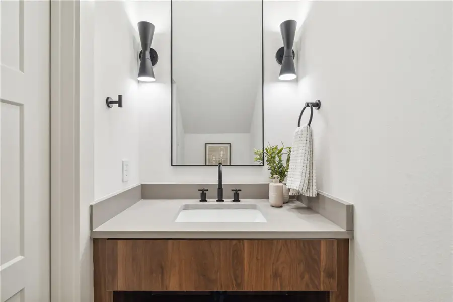 Contrasting finishes and statement lighting elevate the powder room, offering a warm, designer-inspired moment in a compact space. Contrasting finishes and statement lighting elevate the powder room, offering a warm, designer-inspired moment in a compact space.