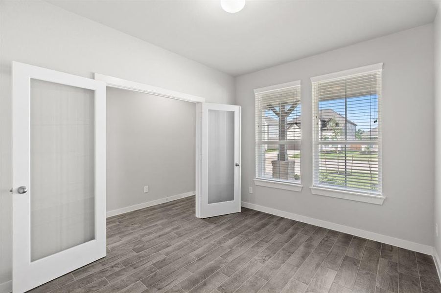 At the forefront, a refined home office beckons productivity and focus. Luxurious details like tile flooring, custom paint, expansive windows with privacy blinds, and French doors create an inspiring workspace. Sample photo of completed home with similar floor plan. As-built interior colors and selections may vary.