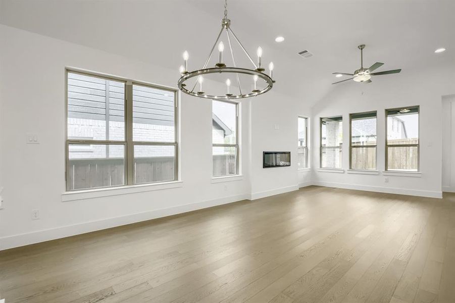Spacious interior featuring wood-finish flooring, a contemporary fireplace, and a vaulted ceiling with a ceiling fan