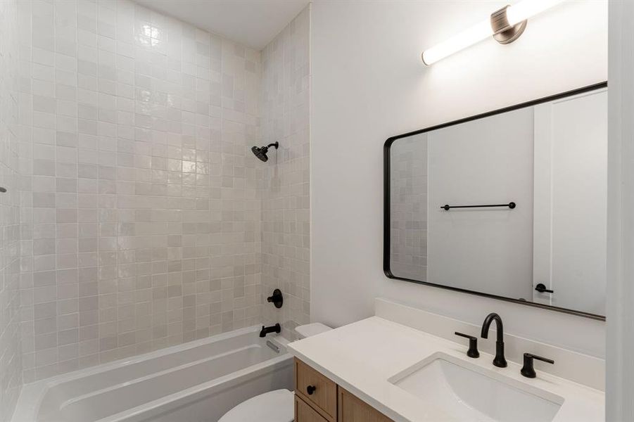 Full bathroom featuring vanity, tiled shower / bath combo, and toilet