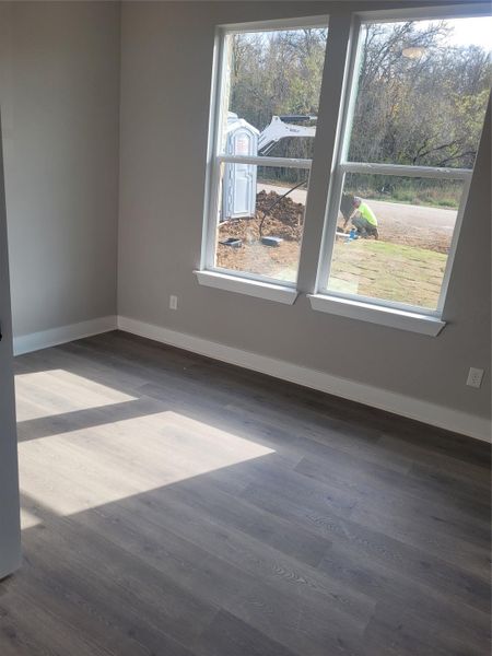 Spare room featuring baseboards and dark wood-style flooring