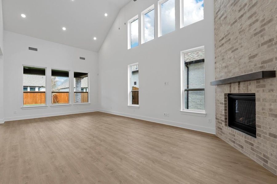 Unfurnished living room featuring high vaulted ceiling, a fireplace, baseboards, and wood finished floors Unfurnished living room featuring high vaulted ceiling, a fireplace, baseboards, and wood finished floors