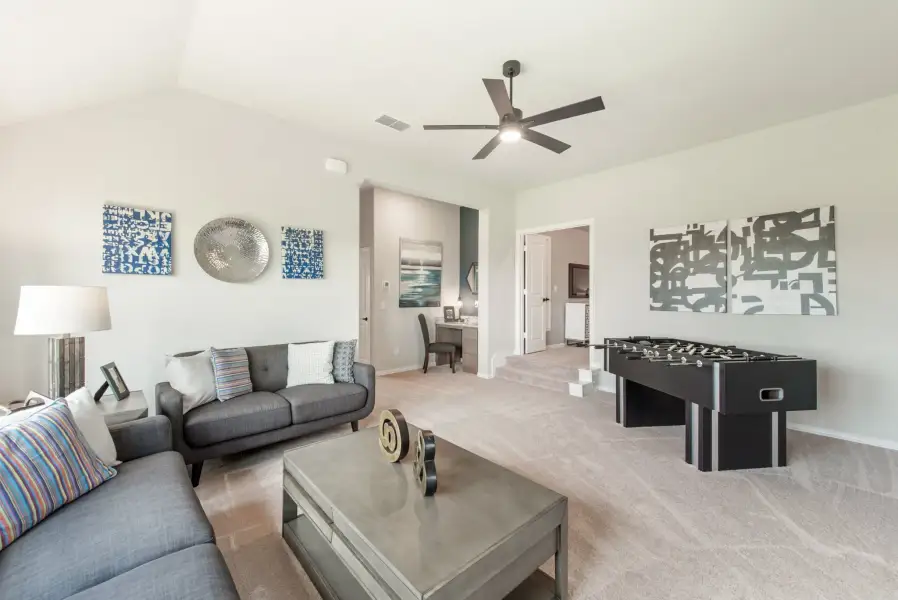 Bonus room with gray sofa, foosball table, ceiling fan, and carpet flooring