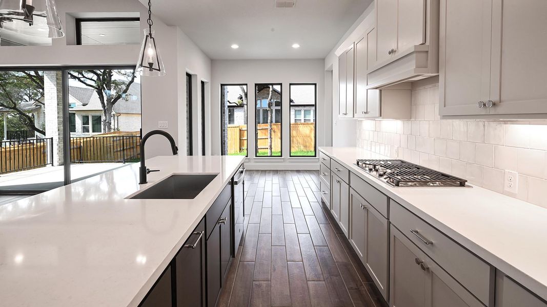 Kitchen featuring dark wood-type flooring, healthy amount of natural light, recessed lighting, stainless steel appliances, and backsplash